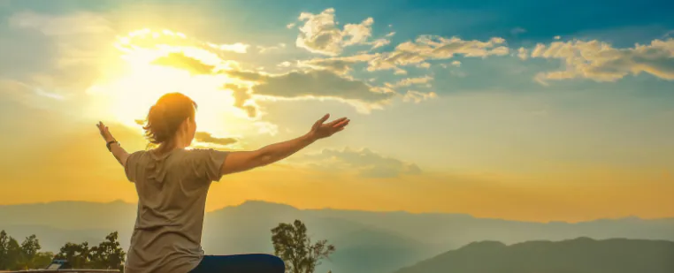 Woman raising her arms toward the rising sun