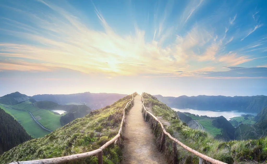 Path through green hills toward a bright sky